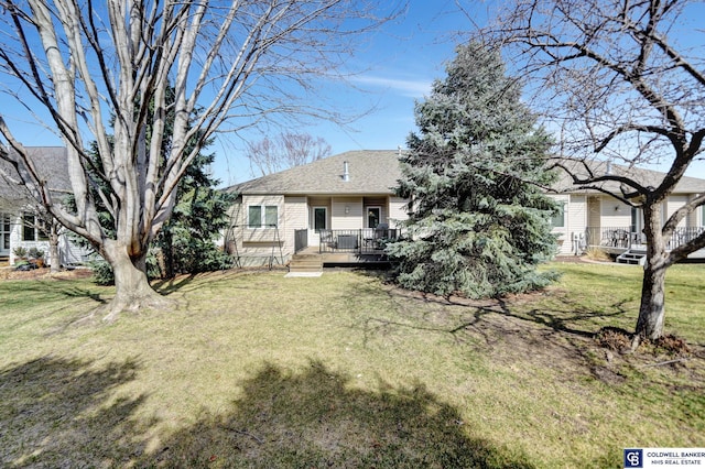 view of front of property featuring a wooden deck, a front yard, and a shingled roof