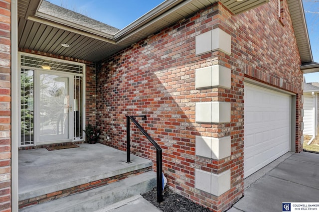 property entrance with a garage, brick siding, and driveway