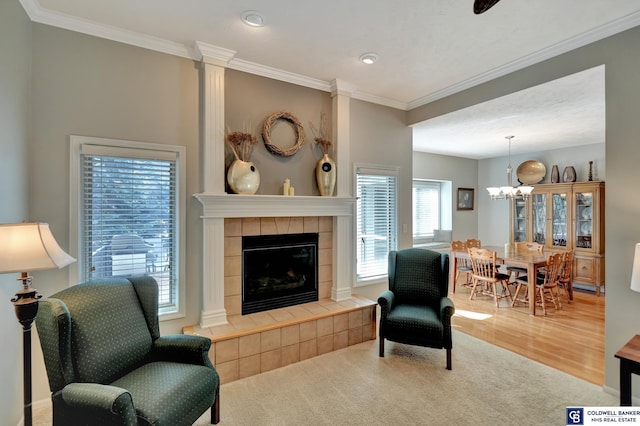 carpeted living area with a notable chandelier, crown molding, and a tiled fireplace