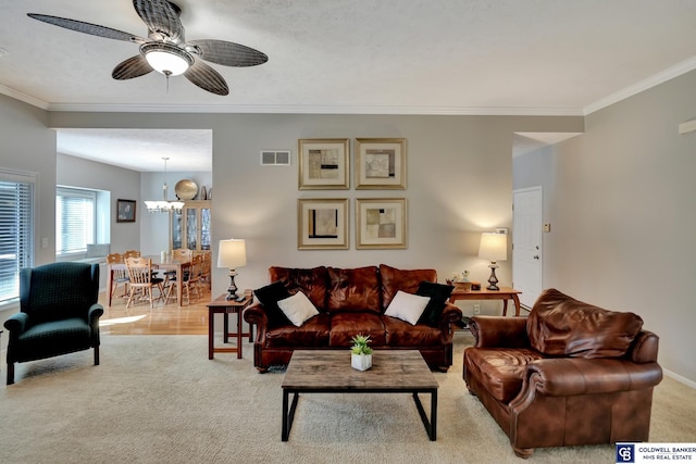 carpeted living room with baseboards, ceiling fan with notable chandelier, visible vents, and ornamental molding