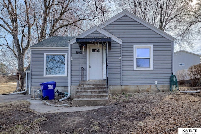 bungalow-style home featuring roof with shingles and entry steps