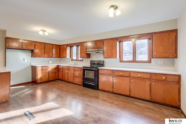 kitchen featuring light countertops, black electric range, brown cabinets, and under cabinet range hood