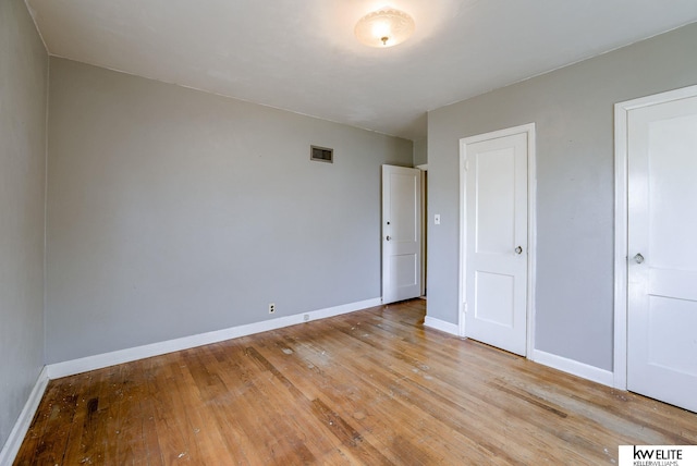 unfurnished bedroom featuring visible vents, light wood-type flooring, and baseboards