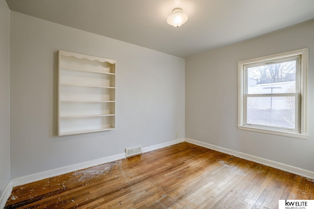 unfurnished room with hardwood / wood-style floors, baseboards, and visible vents