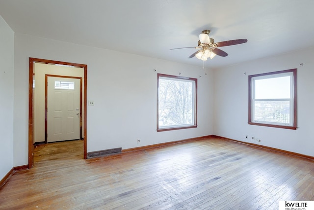 unfurnished room with visible vents, ceiling fan, light wood-type flooring, and baseboards