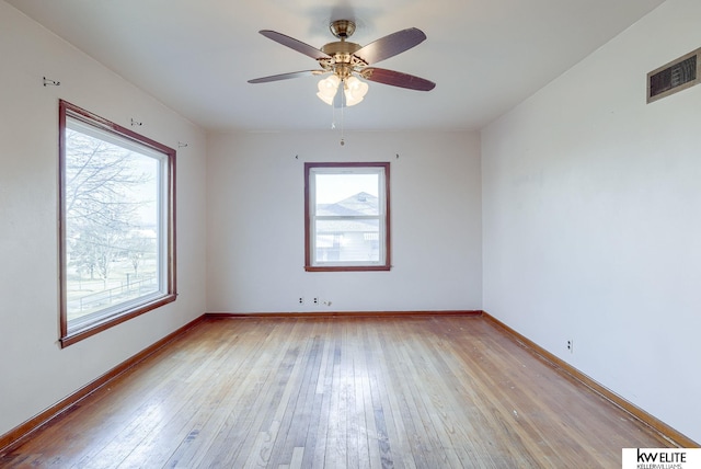 empty room featuring visible vents, ceiling fan, light wood-type flooring, and baseboards