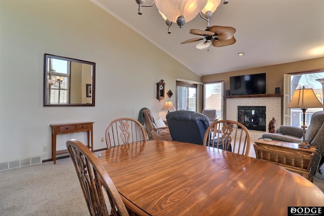 dining space featuring a ceiling fan, baseboards, visible vents, a fireplace, and light carpet