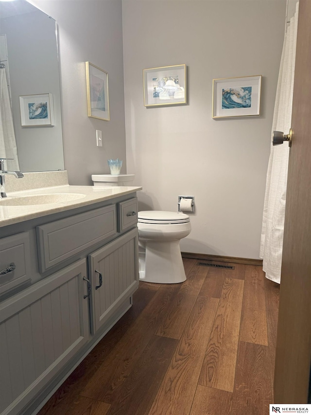 bathroom featuring visible vents, toilet, vanity, and wood finished floors