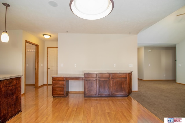 kitchen featuring pendant lighting, light wood-style floors, built in desk, and baseboards