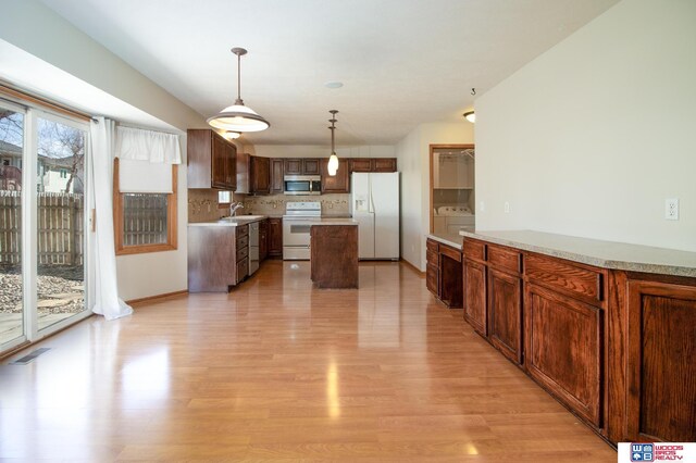 kitchen with white appliances, light wood finished floors, a sink, light countertops, and tasteful backsplash