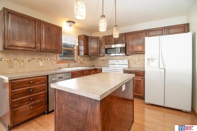 kitchen with light wood finished floors, backsplash, light countertops, appliances with stainless steel finishes, and a sink