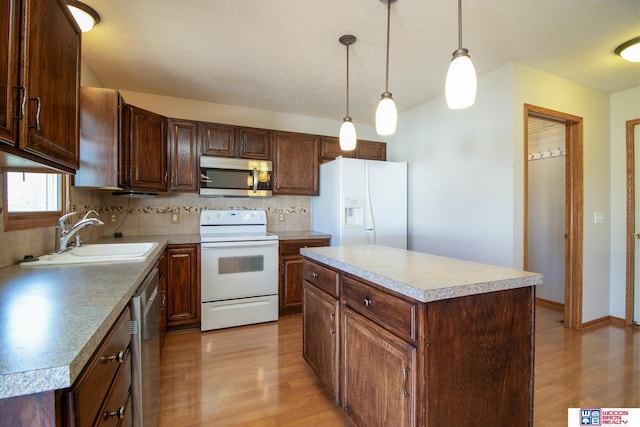 kitchen featuring light wood finished floors, a center island, decorative backsplash, appliances with stainless steel finishes, and a sink