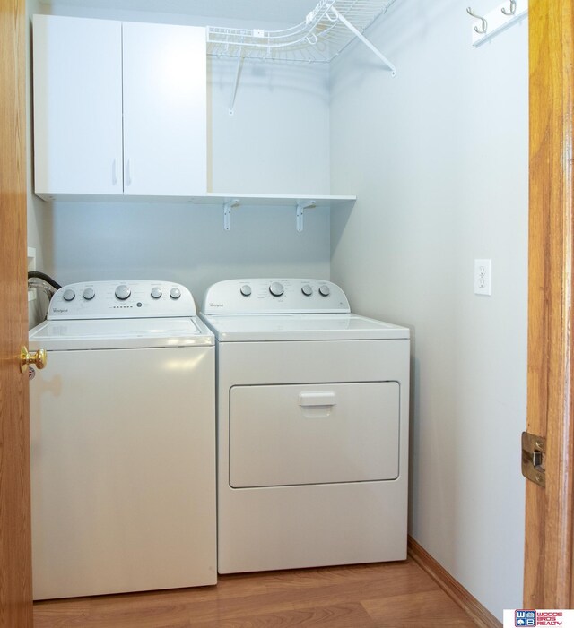 laundry room featuring cabinet space, washer and dryer, light wood-type flooring, and baseboards