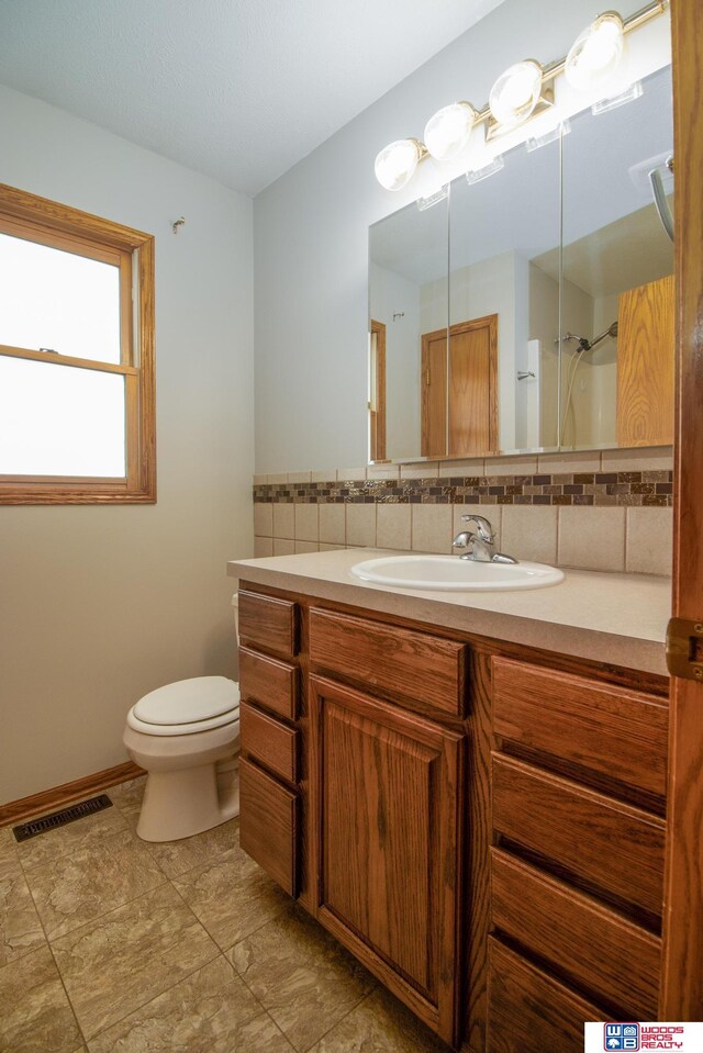 full bath with visible vents, backsplash, baseboards, toilet, and vanity