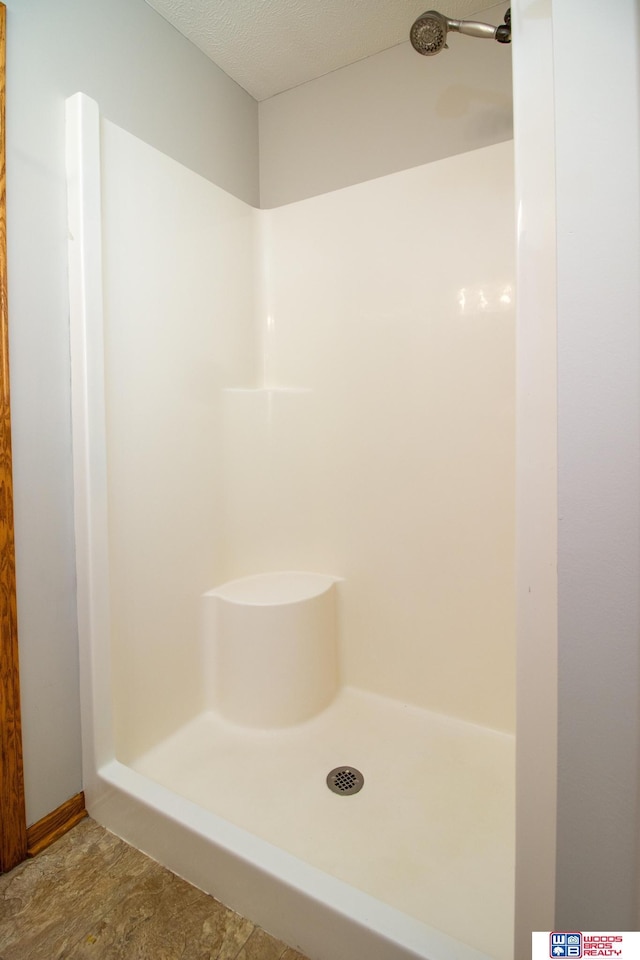 bathroom with a shower stall and a textured ceiling