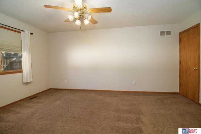 carpeted empty room with visible vents, a ceiling fan, and baseboards