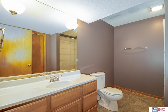 bathroom with baseboards, toilet, vanity, and a textured ceiling