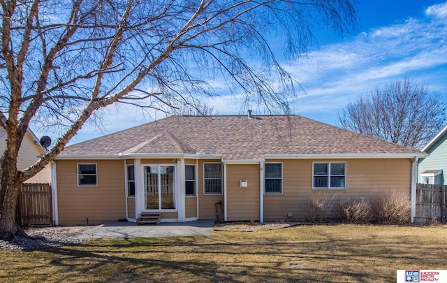 back of house with fence, entry steps, roof with shingles, a lawn, and a patio