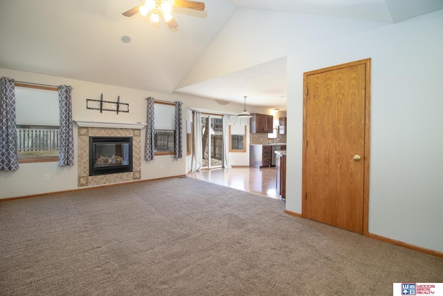 unfurnished living room featuring baseboards, ceiling fan, light colored carpet, a tile fireplace, and high vaulted ceiling