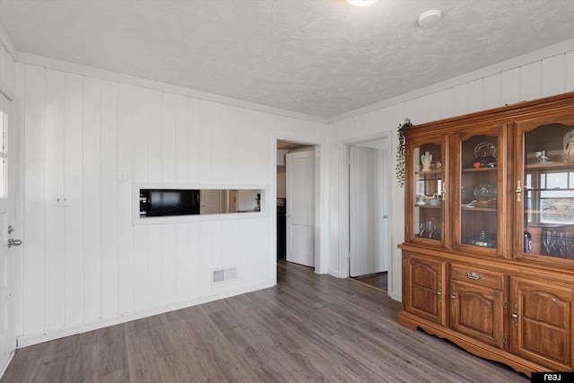 spare room with visible vents, a textured ceiling, and dark wood-style flooring