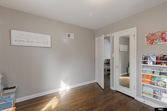 recreation room with dark wood-type flooring, visible vents, and baseboards