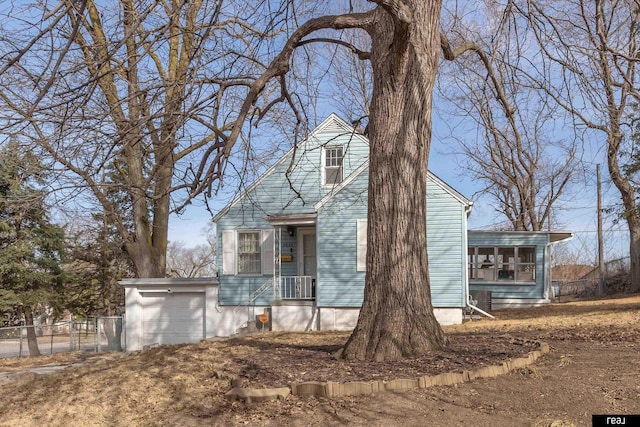 cape cod home featuring fence and a garage