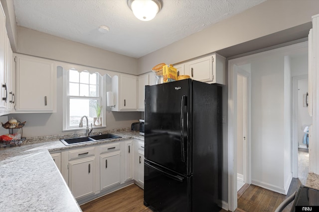 kitchen with a sink, wood finished floors, light countertops, and freestanding refrigerator