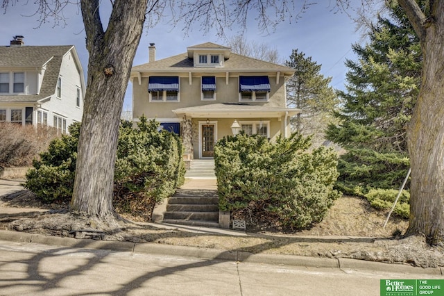 traditional style home with stucco siding, a porch, and a chimney