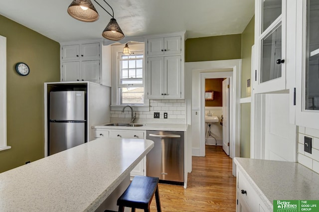 kitchen with a sink, light countertops, appliances with stainless steel finishes, white cabinetry, and tasteful backsplash