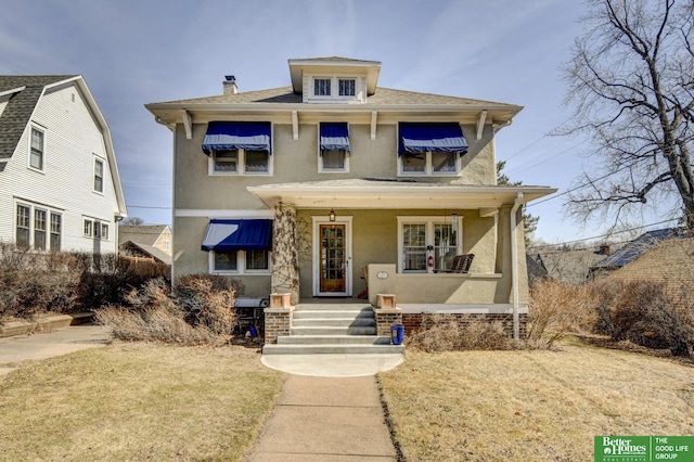 american foursquare style home with covered porch and stucco siding