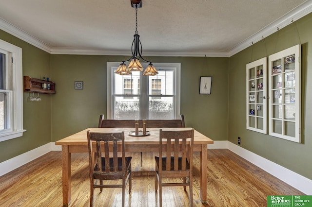 dining area with baseboards, crown molding, and light wood finished floors