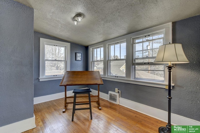 dining room featuring a textured wall, visible vents, a textured ceiling, and hardwood / wood-style flooring