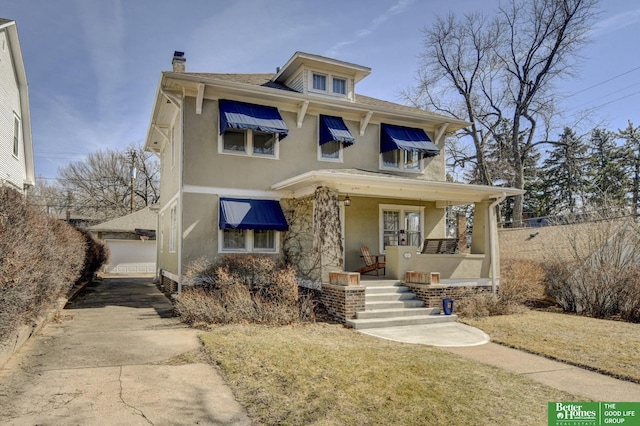 traditional style home featuring stucco siding, covered porch, and a chimney