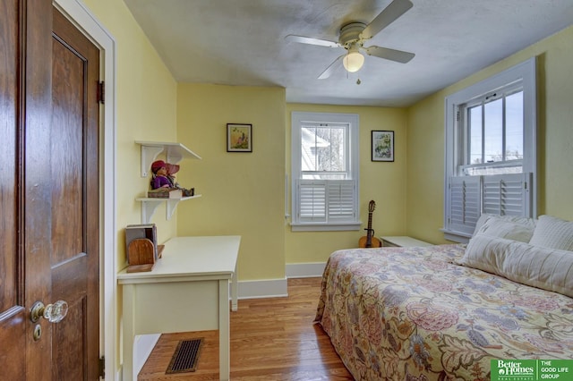 bedroom featuring ceiling fan, wood finished floors, visible vents, and baseboards