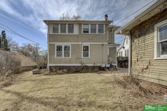 rear view of property featuring stucco siding and a lawn