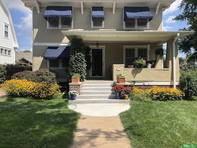 view of front facade with stucco siding, a porch, and a front lawn