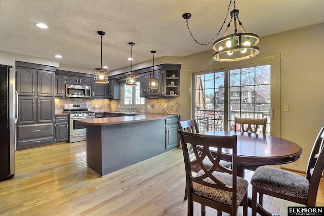 kitchen with light wood-style flooring, open shelves, stainless steel appliances, a peninsula, and decorative backsplash