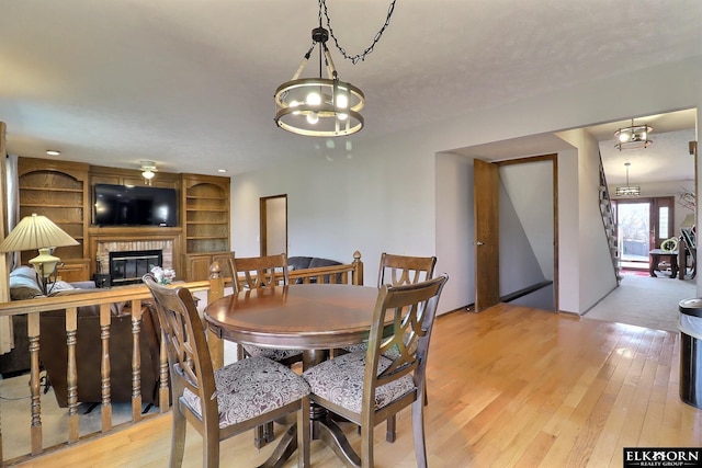 dining room featuring light wood-style flooring and a brick fireplace