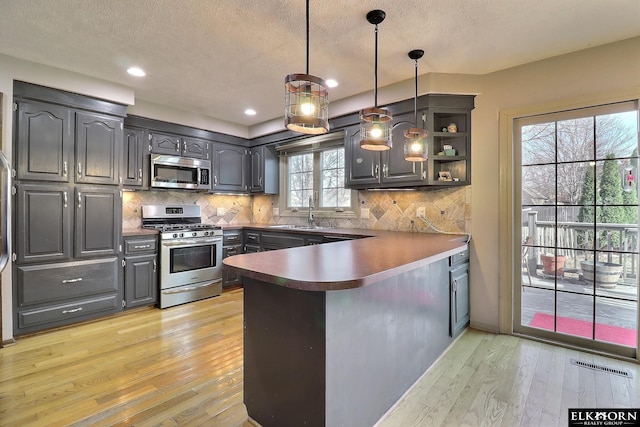 kitchen with tasteful backsplash, visible vents, light wood-style flooring, a peninsula, and stainless steel appliances