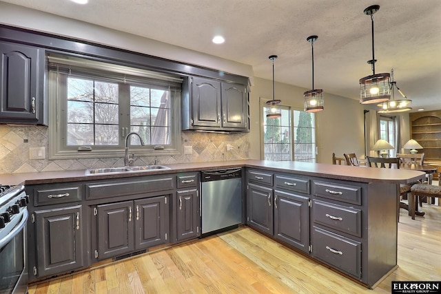 kitchen featuring a peninsula, dark countertops, appliances with stainless steel finishes, and a sink