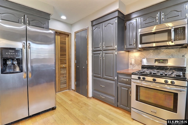 kitchen with decorative backsplash, light wood-style floors, and appliances with stainless steel finishes