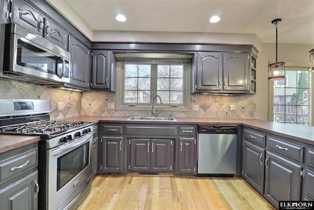 kitchen featuring dark countertops, stainless steel appliances, light wood-type flooring, and a sink