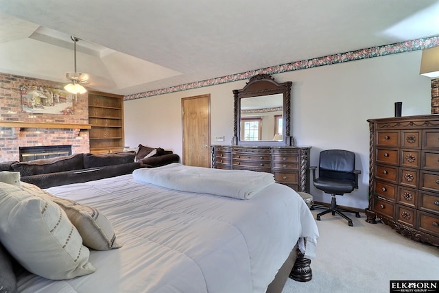 bedroom with a brick fireplace, baseboards, a tray ceiling, and carpet