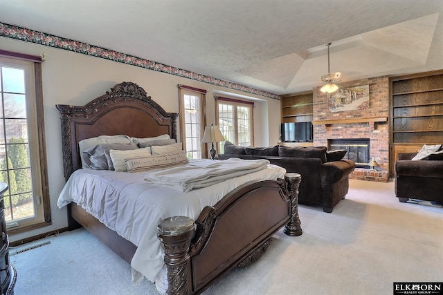 bedroom featuring a brick fireplace, multiple windows, carpet, and visible vents