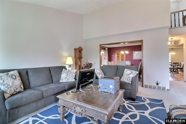 living area with carpet flooring, a high ceiling, a notable chandelier, and visible vents