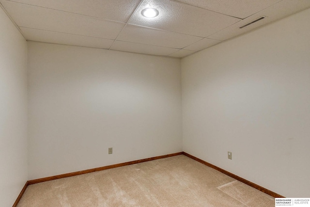 empty room featuring baseboards, a paneled ceiling, light colored carpet, and visible vents