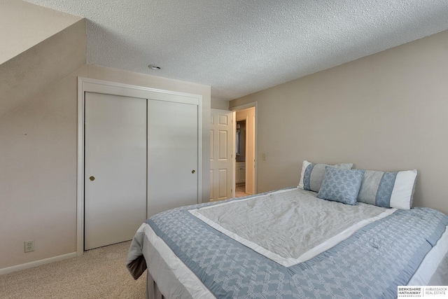 bedroom featuring a closet, light colored carpet, a textured ceiling, and baseboards