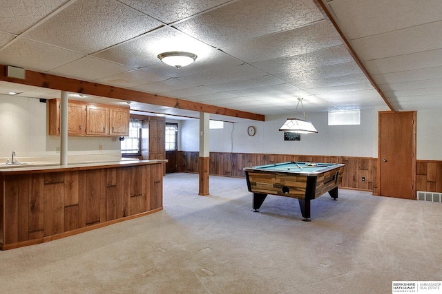 recreation room featuring wooden walls, visible vents, wainscoting, a sink, and light carpet