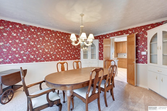 dining space with a wainscoted wall, wallpapered walls, crown molding, light colored carpet, and a chandelier