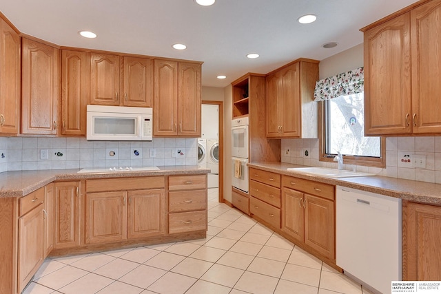 kitchen featuring white appliances, washing machine and dryer, light countertops, and a sink